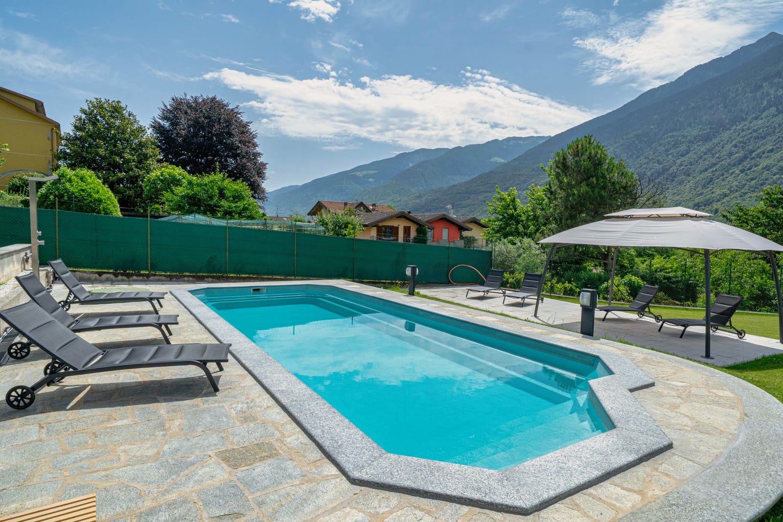 La piscina esterna con solarium e vista sulle Alpi